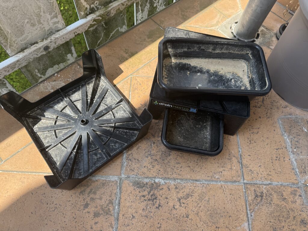 Soiled DrainMaster with soil and lime on a balcony next to a large flower pot